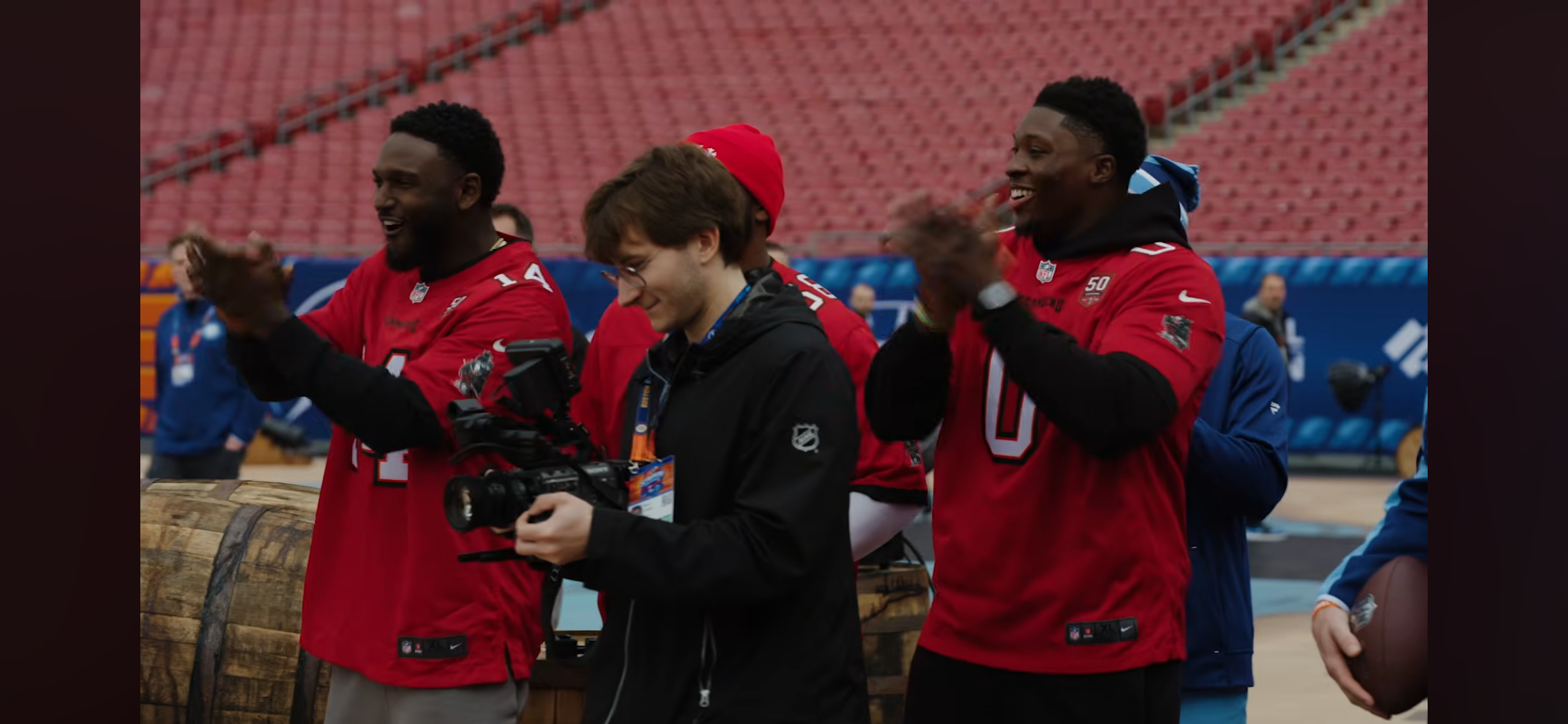 Mack Snider filming on the field with football players around him