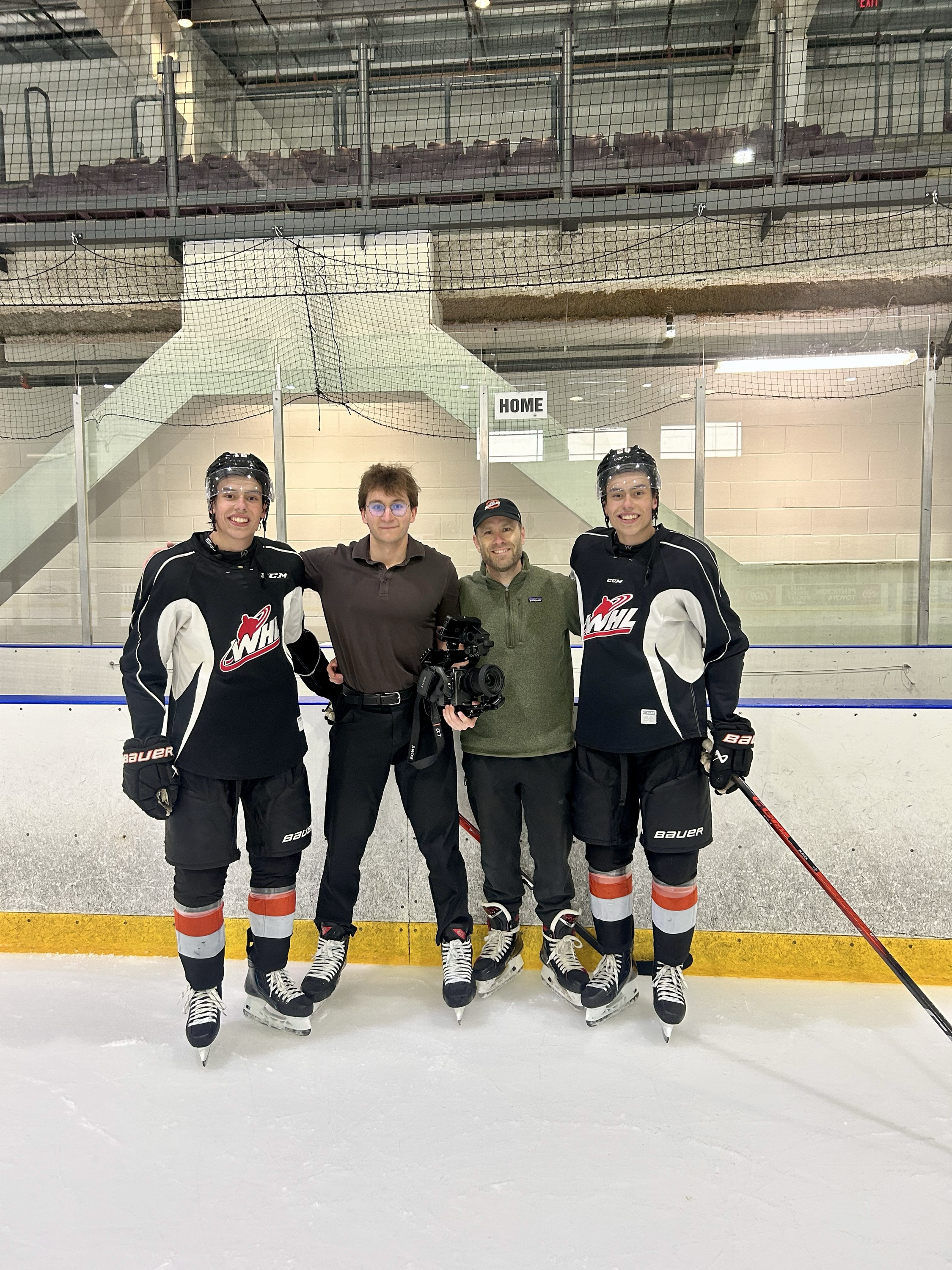 Mack Snider posing on the ice with hockey players and a camera crew
